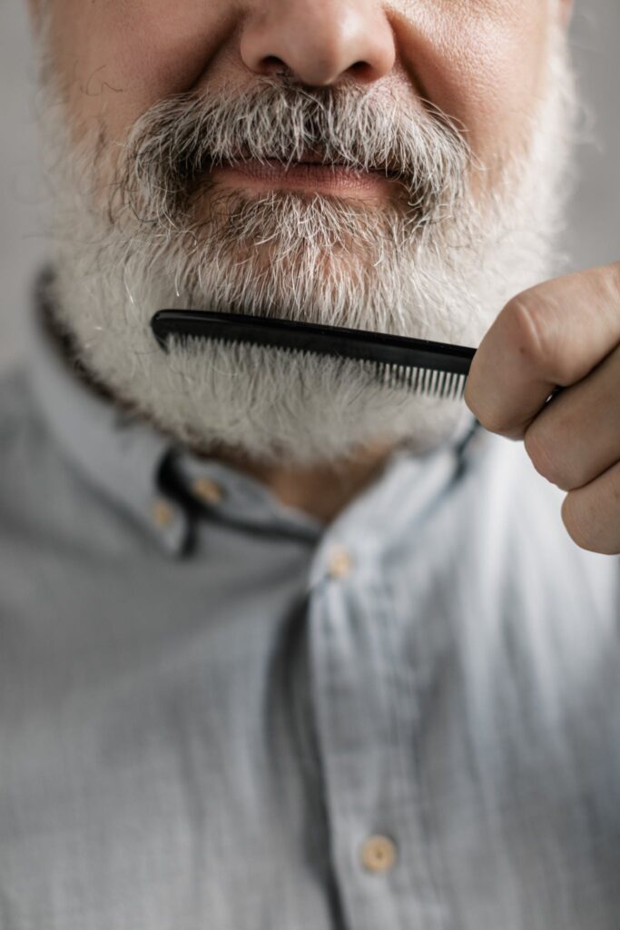 Close-Up Photo of Elderly Man Combing His Beard